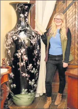  ??  ?? ■ Hansons’ staff member Emma Errington, who is 5ft 5ins, stands next to the vase which was found in a Loughborou­gh bungalow . Picture courtesy of Hansons.