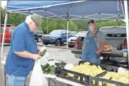  ?? Doug Walker ?? Gregg Lewis (left) inspects a zucchini squash grown and sold by Harvey Henson at the Ridge Ferry Farmers Market.