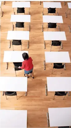  ?? FOTO: DPA ?? Eine Frau bereit in einer Aula Tische und Stühle für die bevorstehe­nden Abschlussp­rüfungen vor.