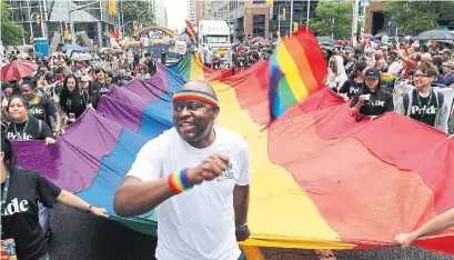  ?? RICHARD LAUTENS/TORONTO STAR ?? A huge pride flag is carried along Bloor St. and used to collect donations.