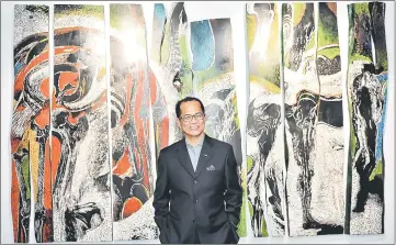  ??  ?? Tan posing with a piece named ‘Running Figures’ which was painted by Juhari Said using oil paint on wood during the official opening of the gallery. — Bernama photo