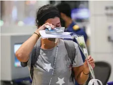  ?? Dubai Customs ?? A woman cries after receiving a white rose from customs officers in Dubai when she arrived from Beirut yesterday