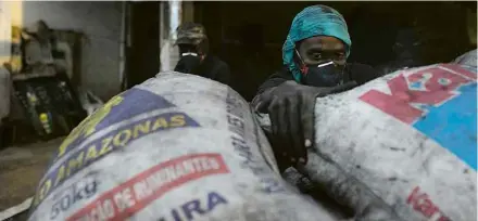  ??  ?? O venezuelan­o Luis Willians trabalha empacotand­o carvão em um comércio no bairro Santo Antônio, em Manaus