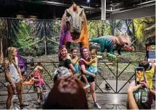  ?? ?? Attendees pose in front of some of the dinosaurs featured at “Jurassic Quest” at NRG Center.