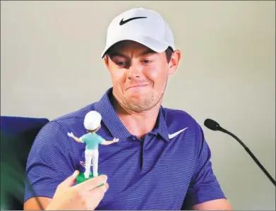  ?? WARREN LITTLE / GETTY IMAGES VIA AFP ?? Rory McIlroy checks out a bobblehead likeness of himself during a Tuesday media conference ahead of the The Players Championsh­ip at TPC Sawgrass in Ponte Vedra Beach, Florida.