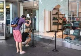  ??  ?? ABOVE LEFT: People take photos Monday of the damaged Macy’s at 835 N. Michigan Ave. in Water Tower Place. ABOVE RIGHT: A crew boards up windows of the Louis Vuitton store at 919 N. Michigan Ave. on Monday.