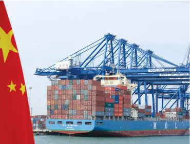  ?? (Bloomberg) ?? A Chinese flag flies on a vessel moving past shipping containers being unloaded at a Tianjin Port Group Co dock in Tianjin, China