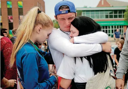  ?? SIMONS, TULSA WORLD] [PHOTO BY MIKE ?? Kiley Landburg, left, Dylan Hurt and Charlee Gilliam mourn Monday on the Northeaste­rn State University campus in Tahlequah.