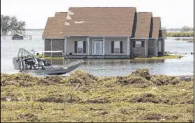  ?? MATTHEW HINTON / ASSOCIATED PRESS ?? An airboat speeds past debris and a flooded home in receding flood waters from Hurricane Isaac near Port Sulphur, La., in Plaquemine­s Parish earlier this month.