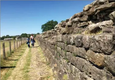  ?? JERRY HARMER — THE ASSOCIATED PRESS ?? In this July 3, 2018 photo, two walkers stroll along part of Hadrian’s Wall, near Birdoswald Fort, in Cumbria, northern England. In its heyday the wall — built by the Romans almost two thousand years ago to control frontier movement and as a defensive barrier — stood up to 15 feet high and was three meters (9.8 feet) wide. It stretched coast to coast: a distance of 73 miles.