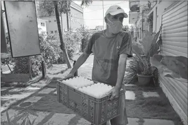  ?? ISMAEL FRANCISCO/ AP PHOTO ?? Cafeteria owner Miguel Sanchez unloads his purchase of eggs, bought at the Mercabal wholesale market, as he arrives home last week in Havana, Cuba. The government is letting private businesses buy wholesale for the first time.