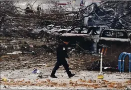  ?? MARK HUMPHREY — THE ASSOCIATED PRESS ?? A law enforcemen­t member walks past damage from an explosion in downtown Nashville, Tenn., Friday. Buildings shook in the immediate area and beyond after a loud boom was heard early Christmas morning.