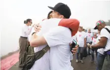  ??  ?? Oscar Padilla (left) embraces Todd Iceton after installing the pink triangle for Pride weekend in San Francisco.