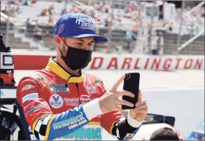  ?? Terry Renna / Associated Press ?? In this May 9 photo, Kyle Larson uses his cell phone before the NASCAR Cup Series auto race at Darlington Raceway in Darlington, S. C. Larson took time out from his NASCAR schedule to Zoom in with the class at Philadelph­ia’s Urban Youth Racing School. The Philly- based program that creates opportunit­ies in racing for minorities extended an olive branch last year to Larson after the driver was caught using a slur during an iRacing event in April.