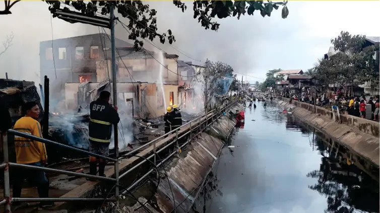  ?? (STEPHANIE V. BERGANIO) ?? FIGHTING FIRE. Firemen and residents struggle to put out a blaze that engulfed some 30 homes in barangays 22 and 26 yesterday afternoon, October 12. The fire started at about 3:31 pm and was declared under control at 4:36 pm and caused damages worth...