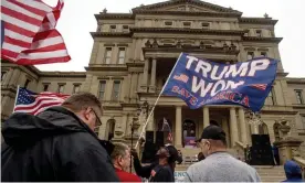  ?? Photograph: Jake May/AP ?? A protester waves a Trump flag during rally at the Michigan State capitol in October.