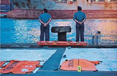  ?? ED WRAY GETTY IMAGES ?? Policemen wait for a navy ship bringing further wreckage of Lion Air flight JT 610 at the Tanjung Priok port on Monday in Jakarta, Indonesia. Lion Air Flight JT 610 crashed shortly after take-off.