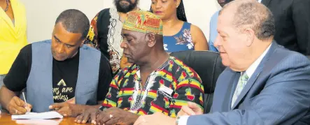  ?? FILE ?? Colonel of the Accompong Maroons, Ferron Williams (centre), watches as president and CEO of Timeless Herbal Care, Courtney Betty (left), signs the tripartite agreement under the Alternate Developmen­t Project at the Ministry of Industry, Commerce, Agricultur­e and Fisheries’ St Lucia Avenue offices in New Kingston on July 8. At right is portfolio minister Audley Shaw. The AD Project is being implemente­d as a strategy to transition traditiona­l cannabis farmers from an illicit framework into the regulated model.