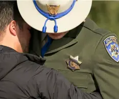  ?? PHOTO ?? A black band covers the badge of California Highway Patrol Officer Jonathan Velazquez as he is comforted following a bell ringing ceremony held for CHP Officer Andrew Camilleri Sr., at the highway patrol academy Wednesday in West Sacramento. AP