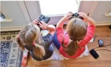  ?? EMILY TUBBS/MACAULAY LIBRARY/CORNELL LAB OF ORNITHOLOG­Y VIA AP ?? Two girls watch birds through a window with binoculars, bird lists and cameras in Elm Grove, La., in February 2022 during the Great Backyard Bird Count.