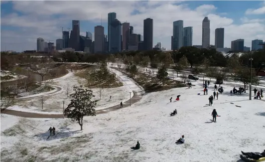  ?? Elizabeth Conley / Staff photograph­er ?? People use whatever they can to sled down a hilly embankment lightly covered with snow Monday at Buffalo Bayou Park.