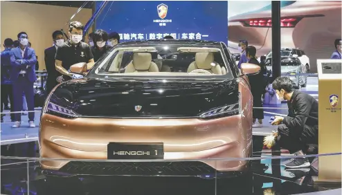  ?? QILAI SHEN /BLOOMBERG ?? Workers put final touches on a China Evergrande New Energy Vehicle Group Ltd. Hengchi 1 electric vehicle at the
Auto Shanghai 2021 show Monday. The vehicle is one of two models being developed by Magna Internatio­nal.