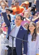  ?? ARIANA CUBILLOS/ASSOCIATED PRESS ?? Venezuela’s self-proclaimed interim president Juan Guaido raises a fist, accompanie­d by his wife Fabiana Rosales, during a rally in Venezuela Tuesday.