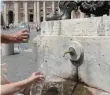  ?? AP ?? Tourists fill their bottles at the drinking fountain next to St Peter’s Square in the Vatican