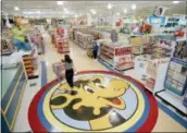  ?? DANIEL HULSHIZER — THE ASSOCIATED PRESS FILE ?? A woman pushes a shopping cart over a graphic of Toys R Us mascot Geoffrey the giraffe at the Toys R Us store in Raritan, N.J.