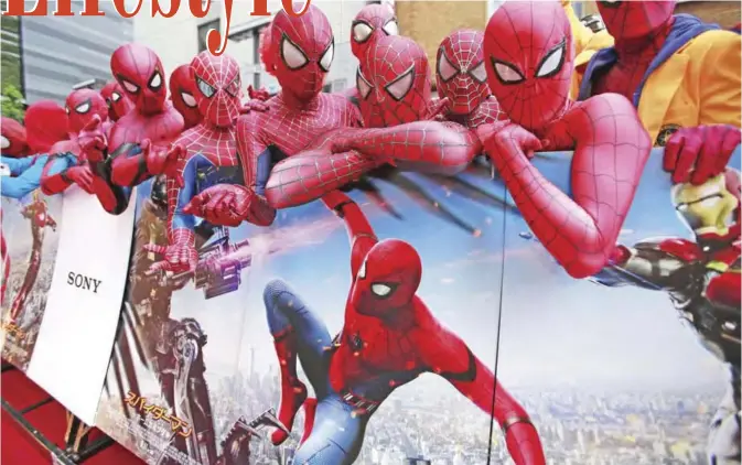  ??  ?? Spider-Man fans dressed as his costume pose with the movie’s posters prior to the Japan premiere for the “Spider-Man: Homecoming” in Tokyo, yesterday. — AP