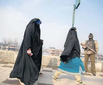  ??  ?? Kashmiri women walk past a paramilita­ry soldier in December in Srinagar.