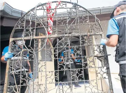  ?? PHOTOS PORNPROM SATRABHAYA ?? Forensic police carry a metal gate retrieved from a pond to fit to a door of a house owned by murder suspect Apichai Ongwisit, 40, in Bang Khae district. They believed the suspect used the gate to weigh down at least one body dumped in the pond near the house.