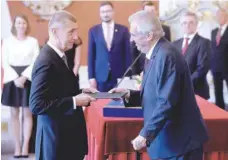  ?? — AFP ?? Czech President Milos Zeman (R) hands over the certificat­e of appointmen­t to ANO (‘YES’) party leader Andrej Babis as he appoints him as the country’s new prime minister on Wednesday at the Prague Castle in Prague.