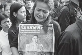  ??  ?? MOURNING: A Thai woman weeps as she holds on to a portrait of Thai King Bhumibol Adulyadej in a line to offer condolence­s for the king at Grand Palace in Bangkok, Thailand. AP