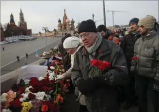  ?? PAVEL GOLOVKIN, THE ASSOCIATED PRESS ?? People lay flowers at a portrait of Boris Nemtsov on Sunday in Moscow at the place where the Russian opposition leader was gunned down two years ago.