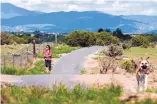  ?? EDDIE MOORE/JOURNAL ?? Deborah Corbett of Santa Fe, shown here walking with her pet Raphael at a dog park in southwest Santa Fe on Monday, loves the park’s new trail, which has been the subject of some debate among park users.