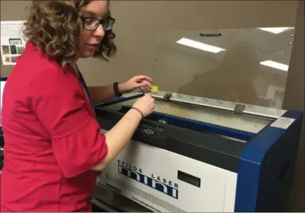  ?? TYLER RIGG — THE NEWS-HERALD ?? Ariel Johnson, a manager at The HUB, engraves a drinking glass with a logo using the laser engraver.