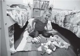  ?? EMILY MICHOT emichot@miamiheral­d.com ?? Brooklyn Grant plays with blocks in the bedroom that she shares with her sister, Addy Stromquist, at their Cocoa, Florida, home.