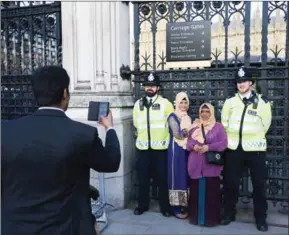  ?? DANIEL LEAL-OLIVAS/AFP ?? People pose for a picture with police officers outside the Houses of Parliament in central London on Sunday.