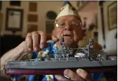  ?? ERIC RISBERG — THE ASSOCIATED PRESS ?? Mickey Ganitch, seen in the living room of his home in San Leandro, holds up a model of the USS Pennsylvan­ia and points to where he served as a lookout during the 1941 attack on Pearl Harbor.