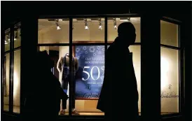  ?? NAM Y. HUH — THE ASSOCIATED PRESS ?? In this Saturday photo, people walk past the window display of a store in Skokie, Ill. A closely-watched gauge for consumer confidence released tumbled to a reading of 88.6 in December as rising coronaviru­s cases tamped down American optimism to its lowest level since summer.