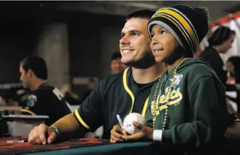 ?? Scott Strazzante / The Chronicle ?? Catcher Josh Phegley introduces himself to A’s fans, including 7-year-old David Avina of Salinas, during last Sunday’s FanFest. Phegley was acquired in the Jeff Samardzija trade.