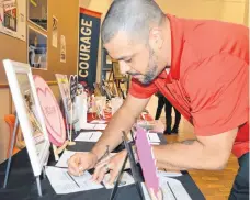  ?? CAPE BRETON POST GREG MCNEIL/ ?? Nick Hareguy places a bid on an item during the silent auction at the NSCC Marconi Campus art sale.