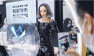  ?? WANG ZHUANGFEI / CHINA DAILY ?? A visitor takes a photo of a bionic robot on Nov 6 at the Microsoft booth during the third China Internatio­nal Import Expo in Shanghai.