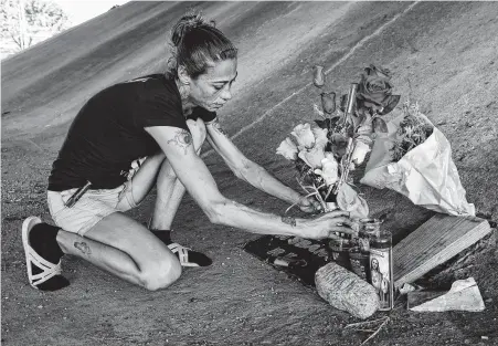  ?? Godofredo A. Vásquez / Staff photograph­er ?? Melissa Fay arranges some flowers for a memorial she built in honor of Michelle Beach and Eugene Stroman under the West Sam Houston Tollway overpass where they were killed by a motorist who crashed into their tent and crushed them.