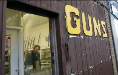  ?? ELAINE THOMPSON — THE ASSOCIATED PRESS ?? This file photo show rifles line a wall above in front of people standing in a gun shop in Seattle. The slaying of five dozen people at a Las Vegas music festival did little to change American opinion about the nation’s gun laws, and the country is...