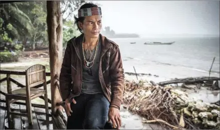  ?? SERGEY PONOMAREV/THE NEW YORK TIMES ?? Esmat Sakulok, a member of the Mentawai tribe and a resident of Jakarta, watches the rain from a guest house on Siberut Island in Indonesia in late July. The Mentawai were finally able to reconnect with their culture after decades of government...