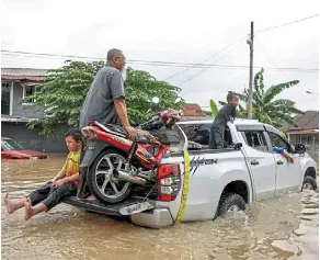 ?? — Bernama ?? Life goes on: a family moving their belongings, including a motorcycle, to higher ground in Kampung padang Jawa, Shah alam.