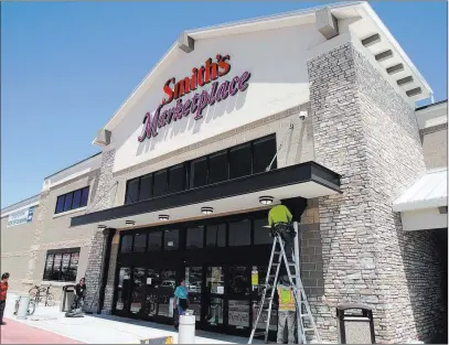  ?? Michael Quine ?? Las Vegas Review-journal Workers from Redd Roofing of Ogden, Utah, put the final touches on the storefront of the new 125,000-square-foot Smith’s Marketplac­e on Skye Canyon Road on Tuesday, the day before its grand opening.