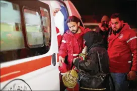  ?? SANA VIA AP ?? Syrian Arab Red Crescent members help a woman holding a baby get into an ambulance during an evacuation of nearly 30 critically ill people this week from eastern Ghouta, near Damascus, Syria. The evacuees were being taken to hospitals.